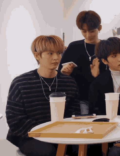 a group of young men are sitting around a table with cups and a tray on it