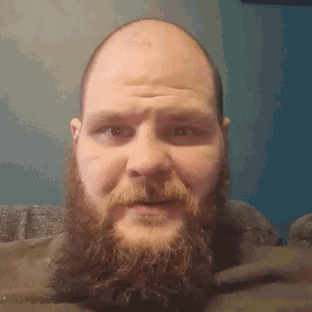 a man with a beard and a bald head looks down at the camera