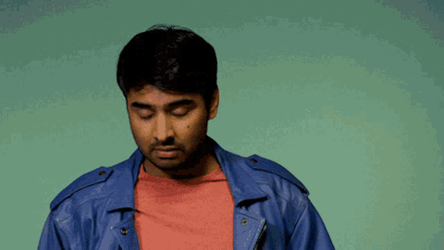 a man wearing a blue leather jacket and a red shirt is looking down