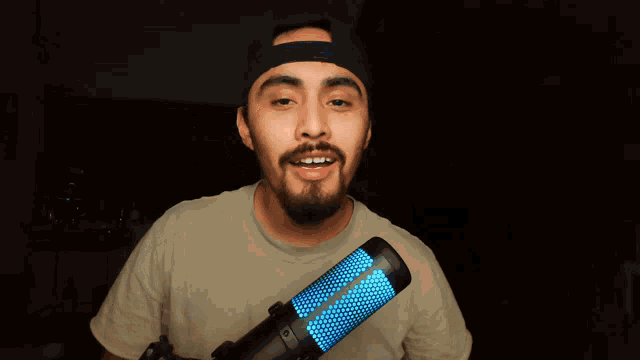 a man with a beard is smiling while holding a microphone that says ' hyperx ' on it