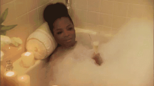 a woman is taking a bubble bath in a bathtub with candles .