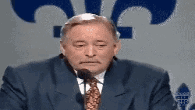 a man in a suit and tie is speaking into a microphone .