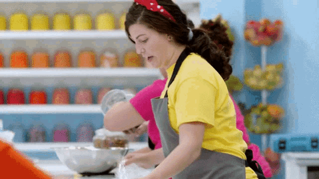 a woman in a yellow shirt and gray apron is cooking