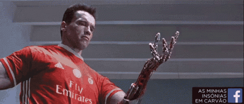 a man wearing a red fly emirates shirt is holding a robotic arm