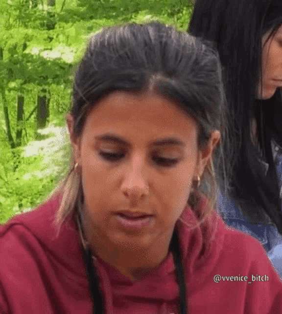 a close up of a woman 's face with a red hoodie on