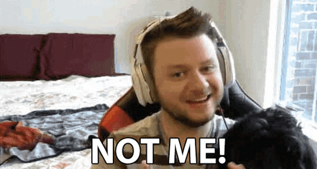 a man wearing headphones is sitting on a bed and saying `` not me ! ''