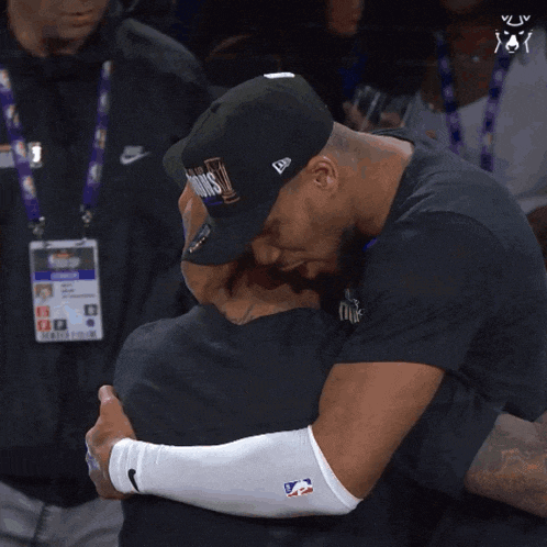a man wearing a hat that says ' kings ' on it hugging another man