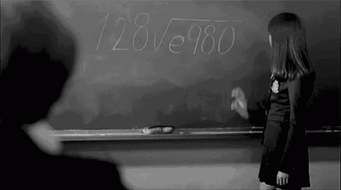 a girl stands in front of a blackboard with the numbers 128 and 980 on it