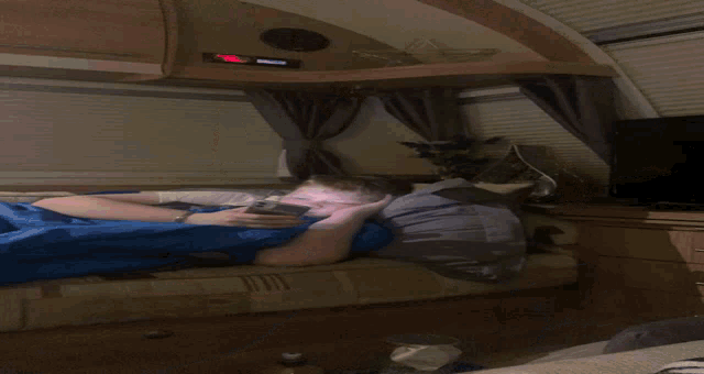 a young boy is laying on a bed looking at his phone
