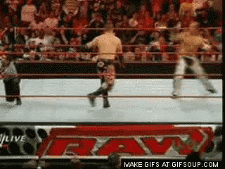 two men are wrestling in a wrestling ring with a crowd watching
