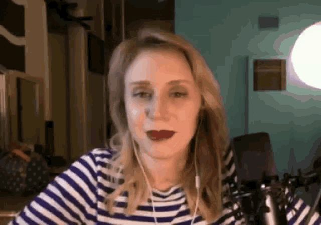 a woman in a striped shirt is wearing headphones and a microphone .