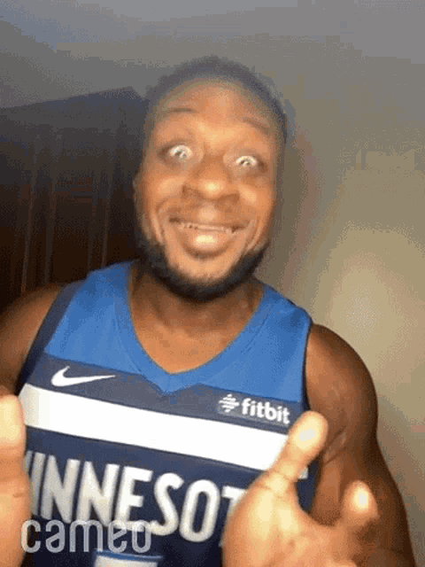 a man in a minnesota basketball jersey is making a funny face .