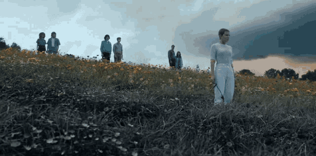 a group of people standing on top of a grassy hill