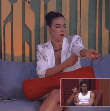 a woman is sitting on a couch with her eyes closed and a picture of a man in a white tank top behind her