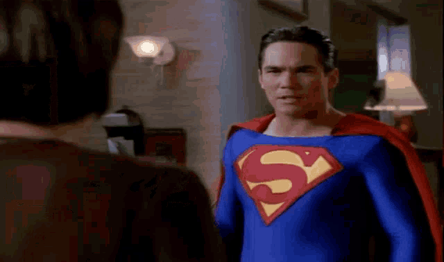 a man in a superman costume is standing next to another man .