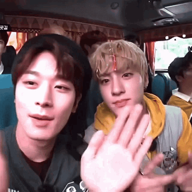a group of young men are sitting in a bus and waving at the camera .