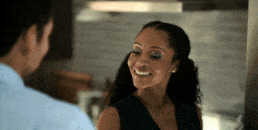 a woman is smiling while looking at a man in a kitchen