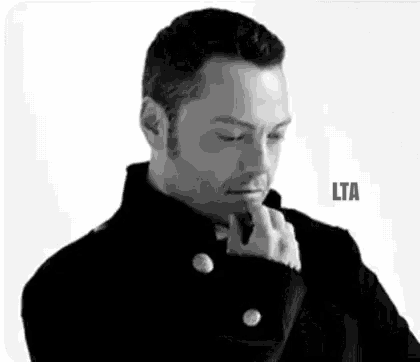a black and white photo of a man with his hand on his chin and the word lta on the bottom .