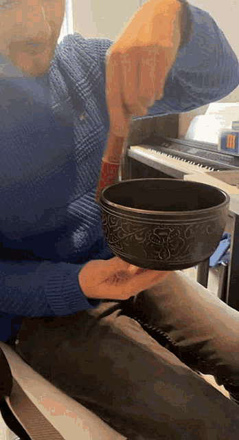 a man is holding a black bowl with a wooden handle