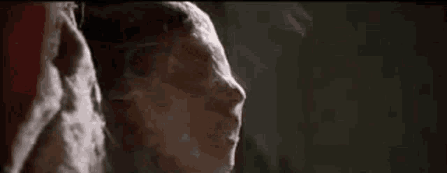 a close up of a man 's face with smoke coming out of his mouth .