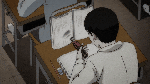 a boy sits at a desk reading a book with a pencil and eraser on it