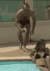 a man in a bathing suit is kneeling next to a woman in a bikini near a swimming pool .