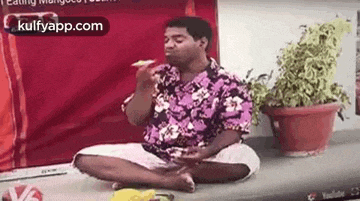 a man is sitting on the floor eating a piece of food .