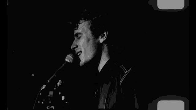 a man singing into a microphone in a black and white photo
