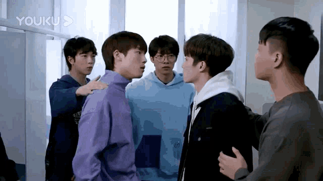 a group of young men are standing in a room with the word youku on the bottom right