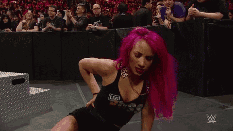 a woman with pink hair is kneeling down in front of a crowd of people .