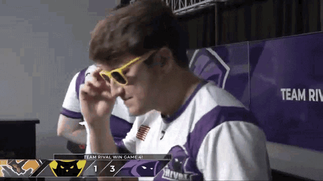 a man wearing sunglasses is sitting in front of a screen that says team rival