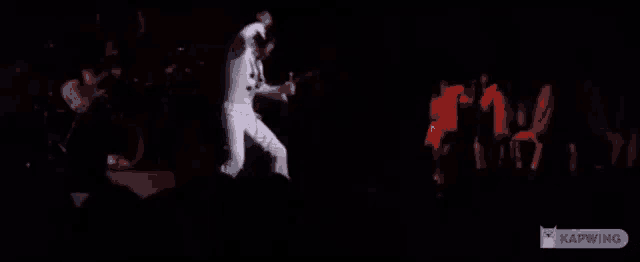 elvis presley is dancing on stage in front of a crowd of people .