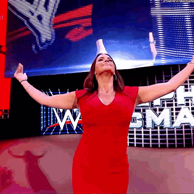 a woman in a red dress stands with her arms outstretched in front of a large w logo