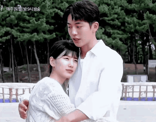 a man and a woman are hugging each other while standing next to each other .