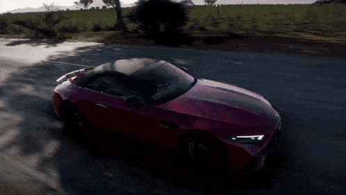 a red sports car with a black top is driving down the road