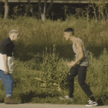 a man in a gray tank top is standing next to another man