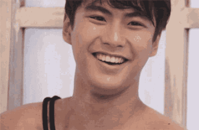 a young man without a shirt is smiling with his teeth showing