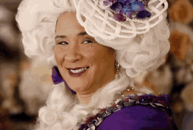 a woman in a white wig and purple dress is smiling