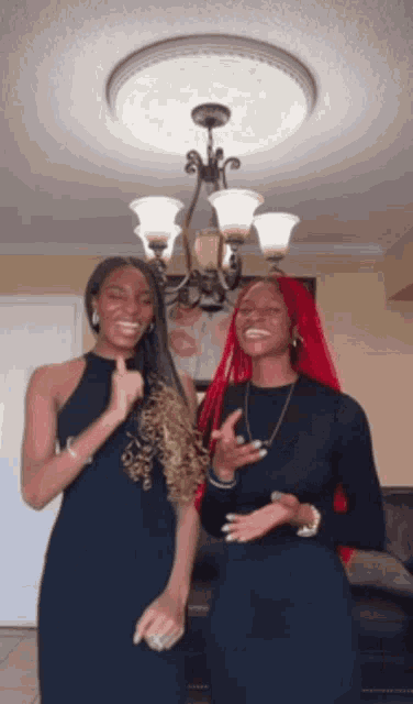 two women are standing next to each other under a chandelier