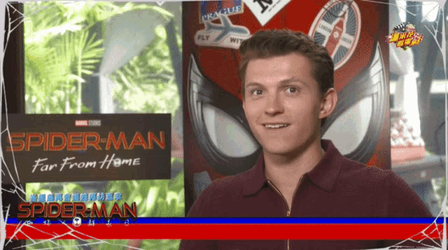 a man stands in front of a spider-man far from home sign