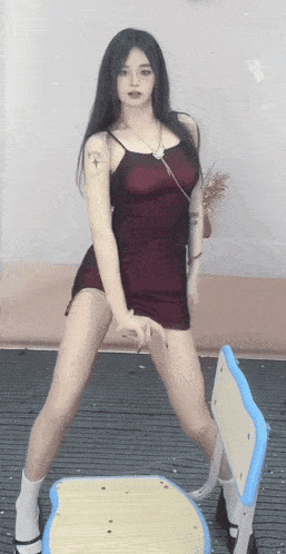 a woman in a red dress is dancing in front of a chair .