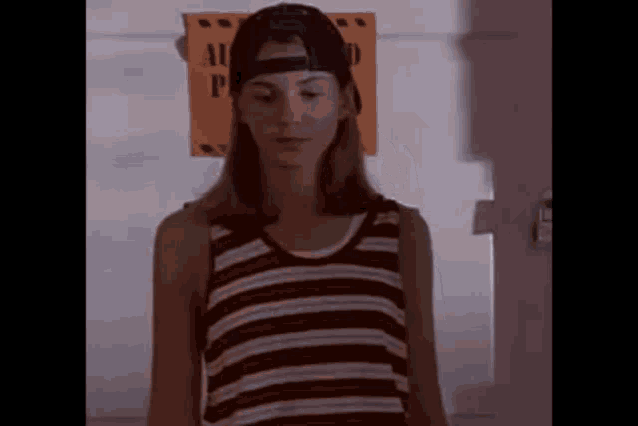 a woman wearing a baseball cap and a striped tank top .