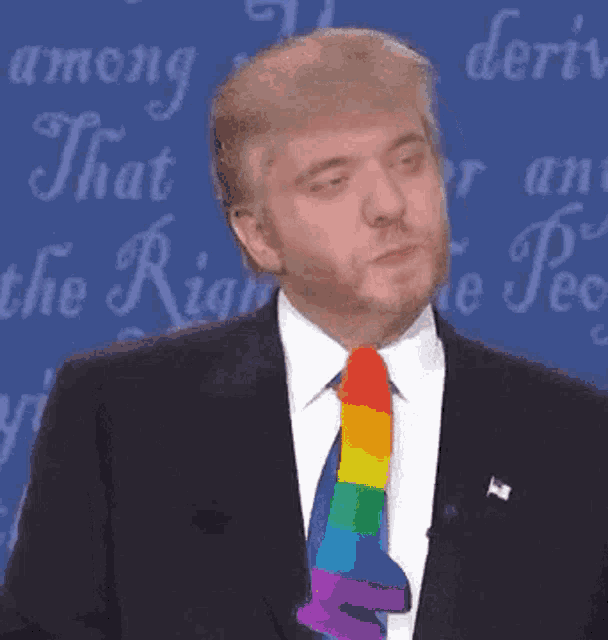 a man in a suit and tie with a rainbow tie stands in front of a sign that says " among that right "