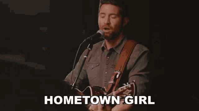 a man singing into a microphone while playing a guitar with the words hometown girl written below him