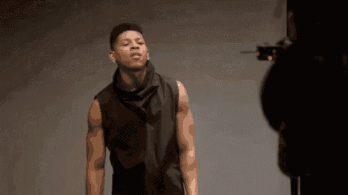 a man is standing in front of a camera while wearing a black vest .