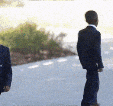 a man in a suit stands next to another man