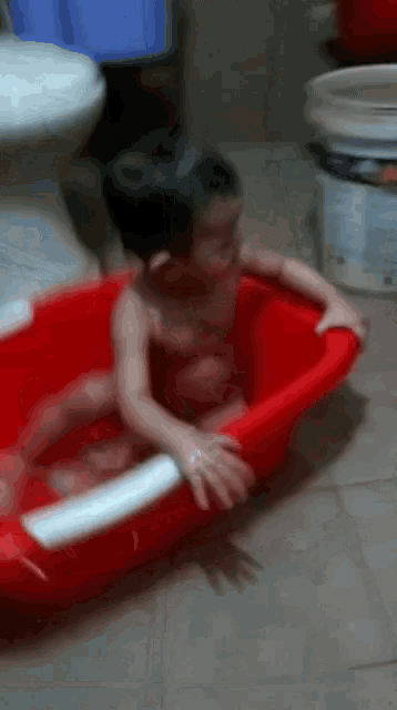 a baby is taking a bath in a red bathtub