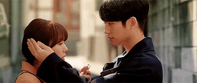 a man and a woman are looking into each other 's eyes and the man is touching the woman 's ear