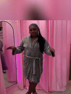 a woman in a robe is standing in front of a mirror in a dressing room