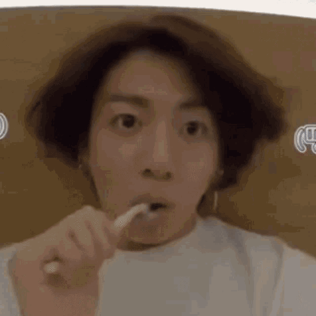 a young man is brushing his teeth with a toothbrush .